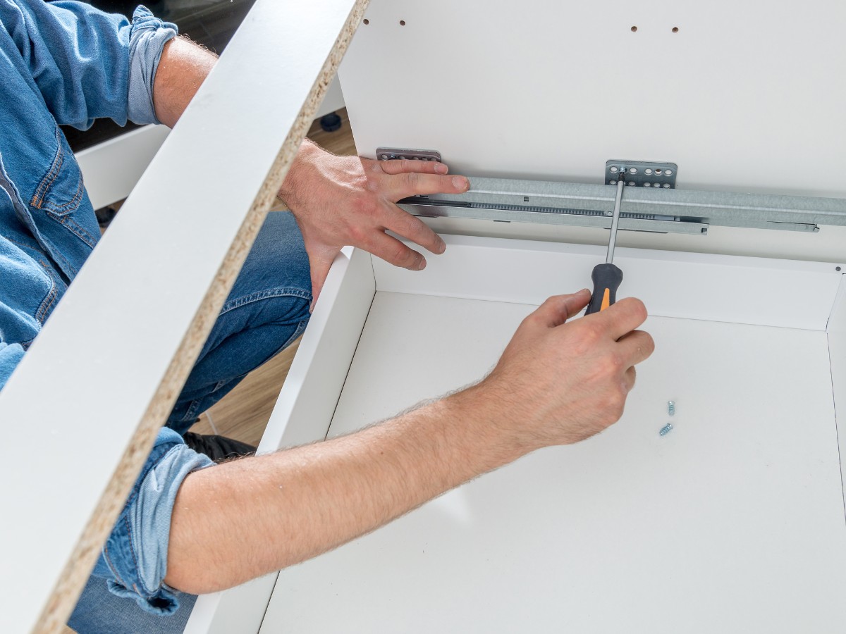 Man fitting a new kitchen drawer, screwing it in