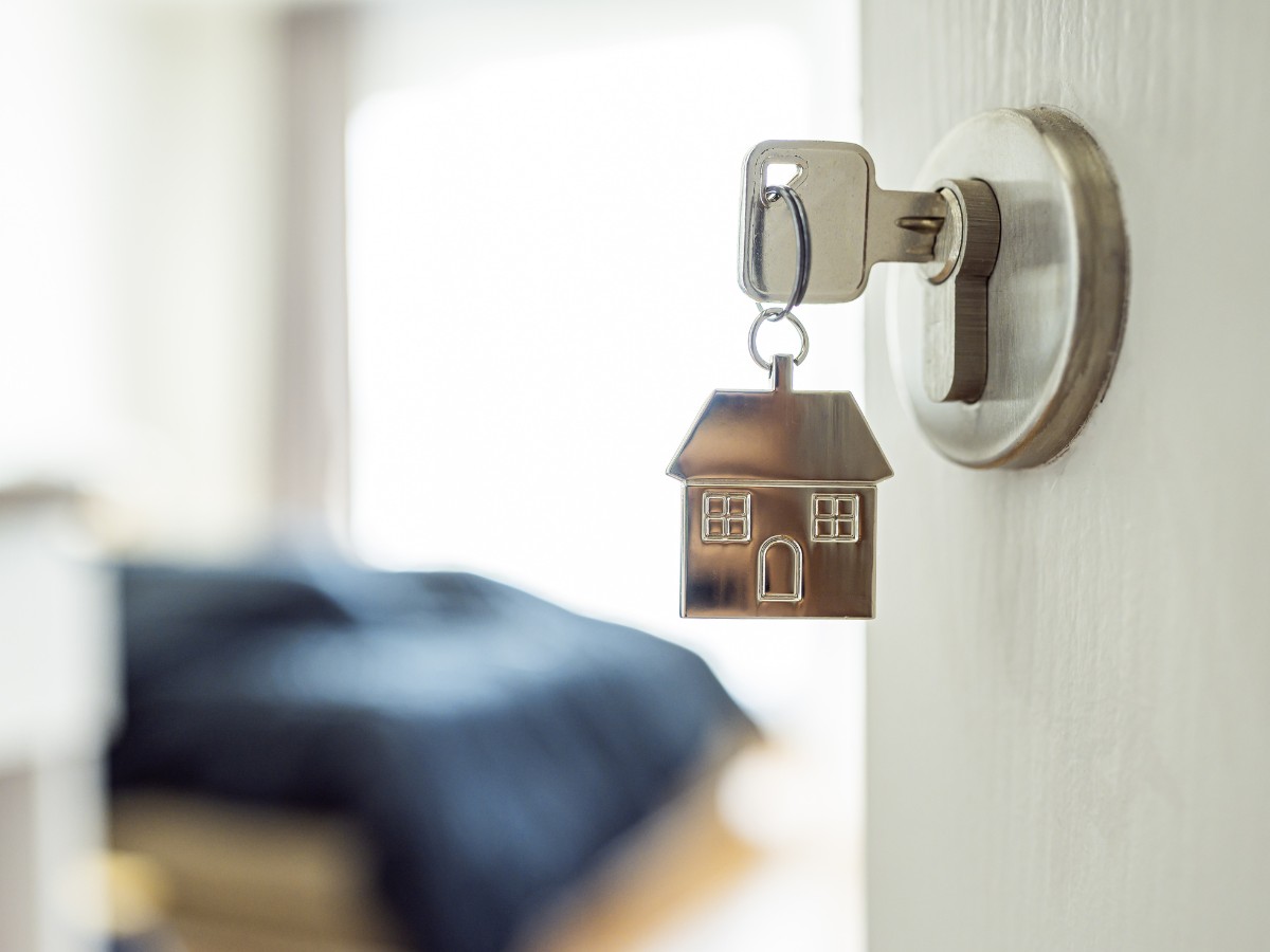 A key in a door with the symbol of a house attached, representing a rental property